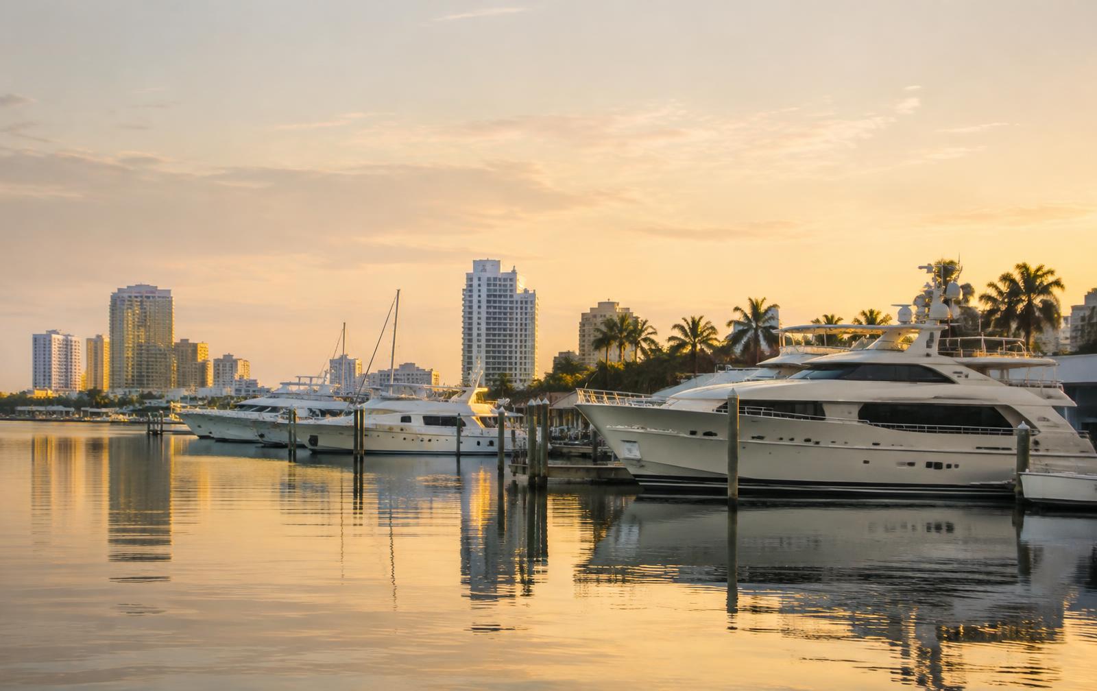 Motor yachts moored at a calm Fort Lauderdale marina at golden hour